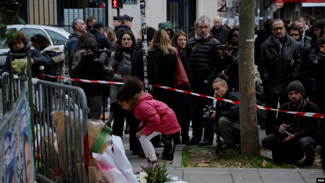 Una niña deja un ramo de flores en honor de las víctimas de los ataques de París.