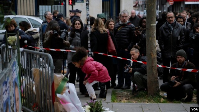 Una niña deja un ramo de flores en honor de las víctimas de los ataques de París.