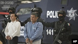 Eduardo Ramirez Valencia, alias 'El Profe,' center, and Ruben Barragan Monterrubi, alias 'El Montes,' are presented to the press at federal police headquarters in Mexico City, Dec 2, 2010