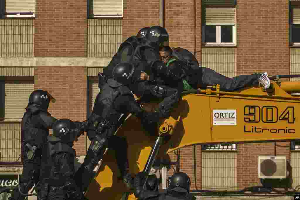 Riot Police remove a housing rights activist who climbed a bulldozer as he tries to stop Luisa Gracia Gonzalez and her family&#39;s eviction and the demolition of their house in Madrid, Spain.