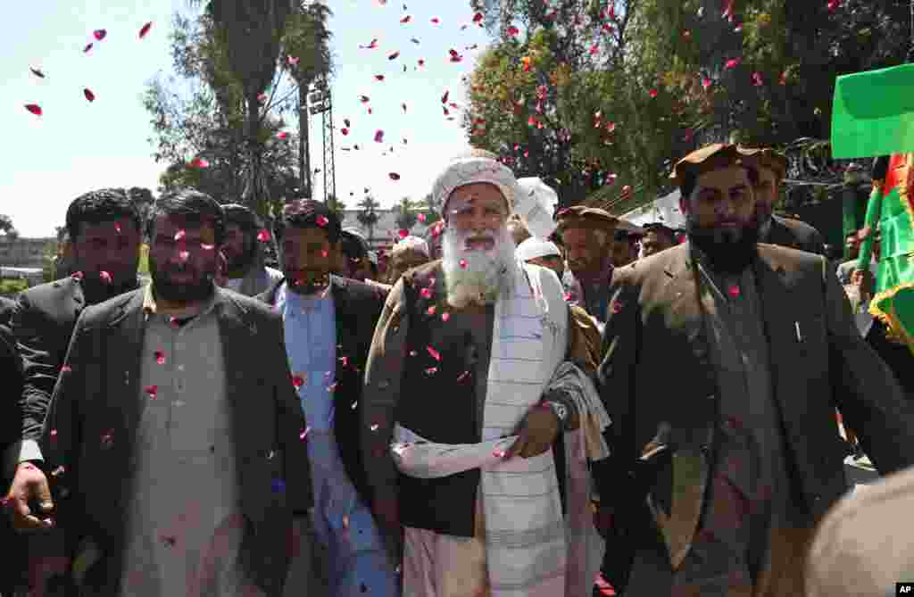 Supporters of presidential candidate Abdul Rasoul Sayyaf throw confetti towards him as they welcome him during a campaign rally in Jalalabad, Afghanistan, April 1, 2014.