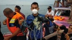 Seorang anggota tim penyelamat yang sedang mencari Sriwijaya Air yang hilang kontak usai lepas landas dari ibu kota Jakarta memegang dugaan puing-puing di laut, 9 Januari 2021, dalam gambar yang diperoleh dari media sosial ini. (Foto: INSTAGRAM @HUMASJAKF