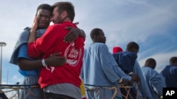 Kybumba Fran, 25, from Cameroon, cries with the head of the mission of Proactive Open Arms NGO Riccardo Gatti, from Italy, as he leaves the Golfo Azzurro rescue vessel after arriving at the port of Pozzallo, south of Sicily, Italy, with more than 220 migr