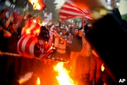 Iranian demonstrators burn representations of the U.S. flag during a protest in front of the former U.S. Embassy in response to President Donald Trump's decision Tuesday to pull out of the nuclear deal and reimpose sanctions, in Tehran, Iran, May 9, 2018.