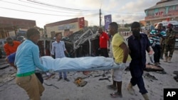 Somalis carry away the body of a civilian who was killed in a car bomb attack in Mogadishu, Somalia, Sept. 28, 2017. Police say the explosion outside a restaurant in Mogadishu's Hamarweyne district has killed at least seven people, mostly civilians.