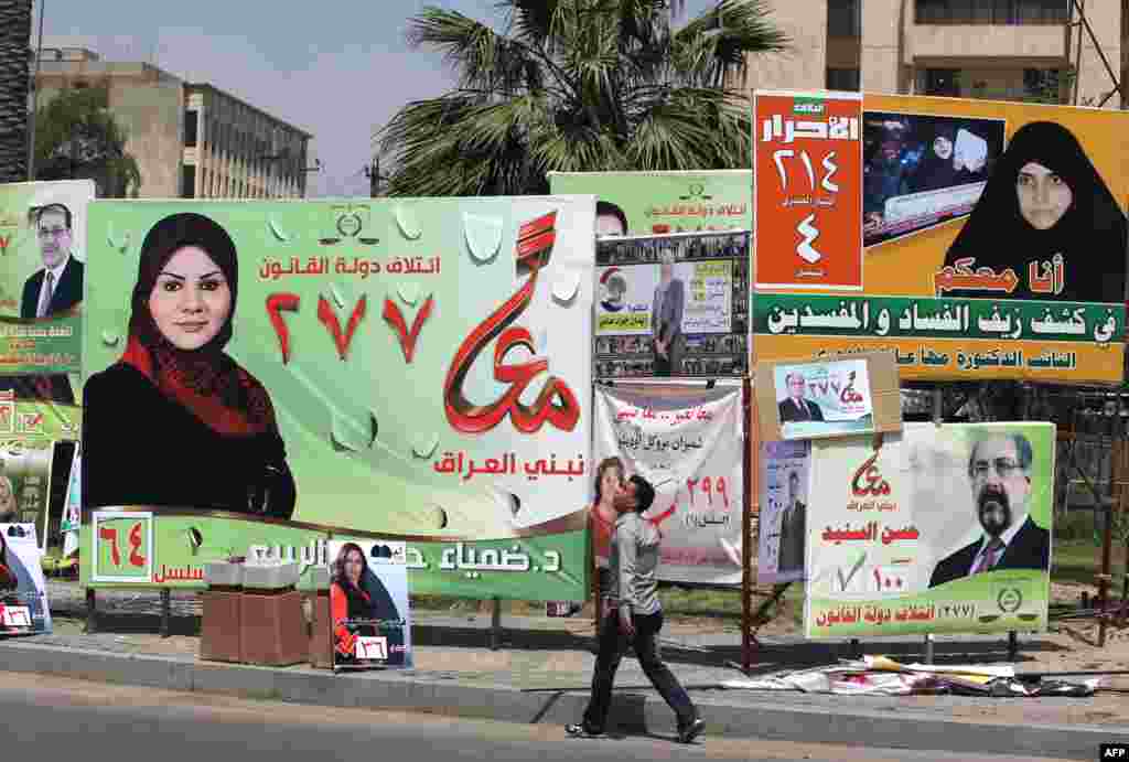 Iraqis walk past election campagin billboards in Kahramana Square in the capital Baghdad.