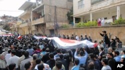 Protesters hold a Syrian flag during a demonstration in Zabadani, near Damascus, April 22, 2011