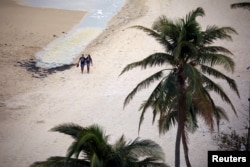 Tourist walk along an empty beach area in San Juan days after Hurricane Maria hit Puerto Rico, Sept. 29, 2017.