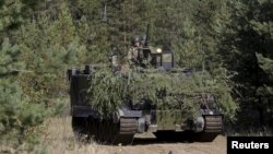 FILE - Danish troops with M113 armored personnel carrier take part in a live fire exercise in a tactical environment ahead of the "Silver Arrow" drill in Adazi training field, Latvia, Sept. 5, 2015. Israel has informed the United States that Lebanese Hezbollah fighters in Syria are using U.S. armored personnel carriers originally supplied to the Lebanese Army.