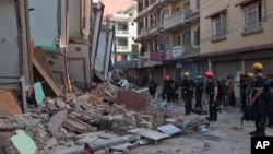 Rescue workers stand beside buildings that collapsed in an earthquake in Kathmandu, Nepal, Tuesday, May 12, 2015. A major earthquake has hit Nepal near the Chinese border between the capital of Kathmandu and Mount Everest less than three weeks after the country was devastated by a quake. (AP Photo/Ranup Shrestha)