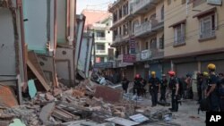 Tim SAR berdiri di dekat bangunan yang roboh akibat gempa di Kathmandu, Nepal (12/5).