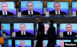 FILE - Visitors walk past TV sets during Russian President Vladimir Putin's live broadcast nationwide phone-in at the DNS electronic shop in Russia's Siberian city of Krasnoyarsk April 17, 2014.