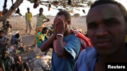 FILE - An illegal immigrant from Ethiopia covers his face as he waits with others for a boat to cross into Yemen outside the town of Obock, north Djibouti. 