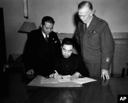 FILE - General Chou En-Lai, representing Communists, signs Cease Fire Order at Chungking, China, January 10, 1946 to bring an end to civil strife in China. General George Marshall, special U.S. envoy to China, right, and Gov. Chang Chun, representing the Nationa