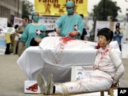 FILE – Falun Gong practitioners simulate organ harvesting in a mock Chinese labor camp in front of the Presidential Office in Taipei, Taiwan, April 23, 2006, in protest against China's suspected abuse and killing of Falun Gong members.