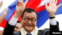 Pemimpin oposisi Kamboja, Sam Rainsy, melambai kepada para pendukungnya di Phnom Penh (19/7). Permohonan Sam Rainsy untuk mencalonkan diri dalam pemilu parlemen ditolak.
