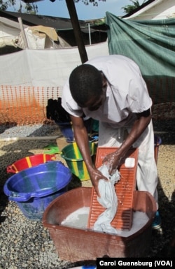 A worker scrubs uniforms and other items at the Doctors Without Borders Ebola treatment center in Conakry, Guinea.