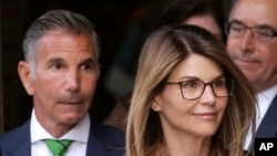 FILE - Actress Lori Loughlin, front, and husband, clothing designer Mossimo Giannulli, left, depart federal court in Boston after facing charges in a nationwide college admissions bribery scandal, Apr. 3, 2019.