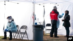 在离白宫不远的华盛顿市法拉格特广场的一处新冠病毒检测站，一名工作人员稍事休息，一名民众同时上前接受检测。(2021年12月23日)