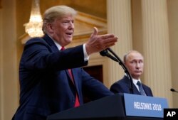 U.S. President Donald Trump, left, gestures while speaking as Russian President Vladimir Putin looks on during their joint news conference at the Presidential Palace in Helsinki, Finland, July 16, 2018.