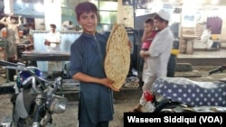 ایک نوعمر لڑکا قندھاری نان دکھاتے ہوئے