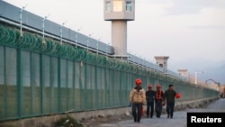 Công nhân đi ngang tường rào của một nơi được chính thức gọi là trung tâm dạy nghề ở Urumqi, thủ phủ của Khu Tự trị Uighur Tân Cương, ngày 4 tháng 9, 2018.