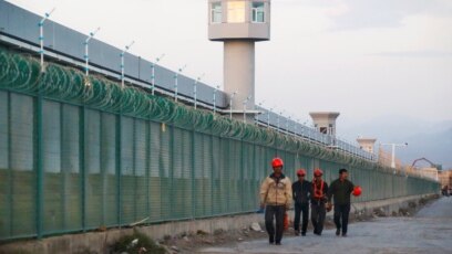 Công nhân đi ngang tường rào của một nơi được chính thức gọi là trung tâm dạy nghề ở Urumqi, thủ phủ của Khu Tự trị Uighur Tân Cương, ngày 4 tháng 9, 2018.