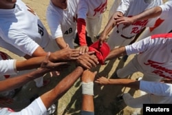 FILE - Members of Family Rose softball team put their hands together before a match at Lecuna Avenue softball pitch in Caracas, Venezuela, March 24, 2019. After the game we always had a few beers. But now they are too expensive," said Felix Babaza.
