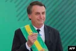 Brazil's new President Jair Bolsonaro poses with the pen used during the swearing-in ceremony for the minsters at the Planalto Palace in Brasilia, Jan. 1, 2019, after his own inauguration at the national Congress.