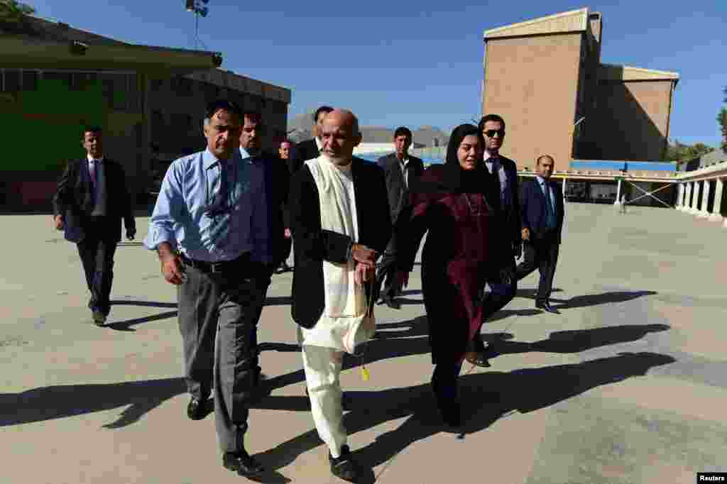 Afghan President Ashraf Ghani walks with teachers in the courtyard during his visit to the Amani High School in Kabul, Sept. 30, 2014.