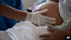 FILE - In this July 25, 2012 file photo, a pregnant woman is examined as she waits to give birth at a public hospital in Rio de Janeiro. 