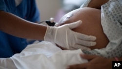 FILE - In this July 25, 2012 file photo, a pregnant woman is examined as she waits to give birth at a public hospital in Rio de Janeiro. 