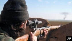 A militant fighter aims a sniper rifle during fighting in Tal Tamr, Hassakeh province, Syria, in this image posted by the Al-Baraka division of the Islamic State group, Feb. 24, 2015.