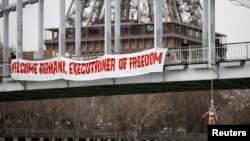 FILE - An activist hangs from a bridge to protest Iran's President Hassan Rouhani visit to Paris, January 28, 2016.