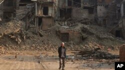 FILE - A Nepalese man walks past damaged houses one month after the deadly 7.8 magnitude earthquake in Kathmandu, Nepal, May 25, 2015. 