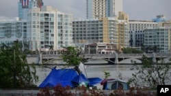 FILE - Tents stand on the other side of the shore of Laguna de Condado opposite the exclusive area of ​​Paseo Caribe in San Juan, Puerto Rico, Oct. 23, 2017. 