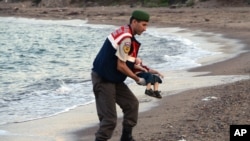 A paramilitary police officer carries the lifeless body of an unidentified migrant child, lifting it from the seashore near the Turkish resort of Bodrum, Sept. 2, 2015.