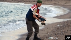 A paramilitary police officer carries the lifeless body of a migrant child, later identified as that of three-year-old Aylan Al Kurdi, near the Turkish resort of Bodrum, Sept. 2, 2015.