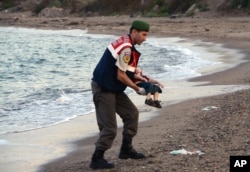 A paramilitary police officer carries the lifeless body of an unidentified migrant child, lifting it from the seashore near the Turkish resort of Bodrum, Sept. 2, 2015.