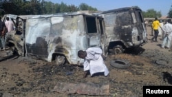 A boy searches the ground next to a burnt-out vehicle, caused by an attack from Boko Haram militants, in Bama, Borno State, Nigeria, Feb. 20, 2014.