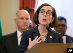 Oregon Gov. Kate Brown, center, discusses climate change at a news conference held by California Gov. Jerry Brown, left, June 13, 2017, in Sacramento, California.