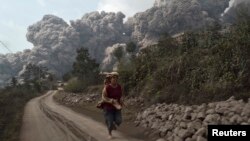 Seorang warga desa berlari menghindari letusan Gunung Sinabung di desa Sigarang-Garang, distrik Karo, Sumatera Utara (1/2).