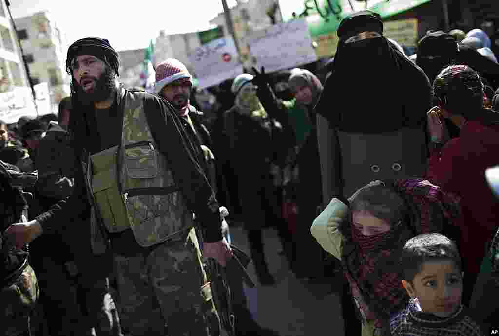 A Free Syrian Army fighter stands among protesters during an anti-government protest in north Syria. (AP)
