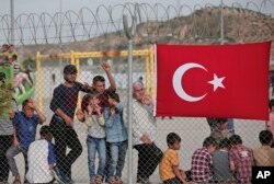 Migrants stand behind a fence at the Nizip refugee camp in Gaziantep province, southeastern Turkey, April 23, 2016.