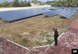 FILE - A member of the Taiwan coast guard shows the solar panels used for electrical power to visiting media on Taiping island, also known as Itu Aba, in the Spratly archipelago, roughly 1,600 kilometers (1,000 miles) south of Taiwan, March 23, 2016.