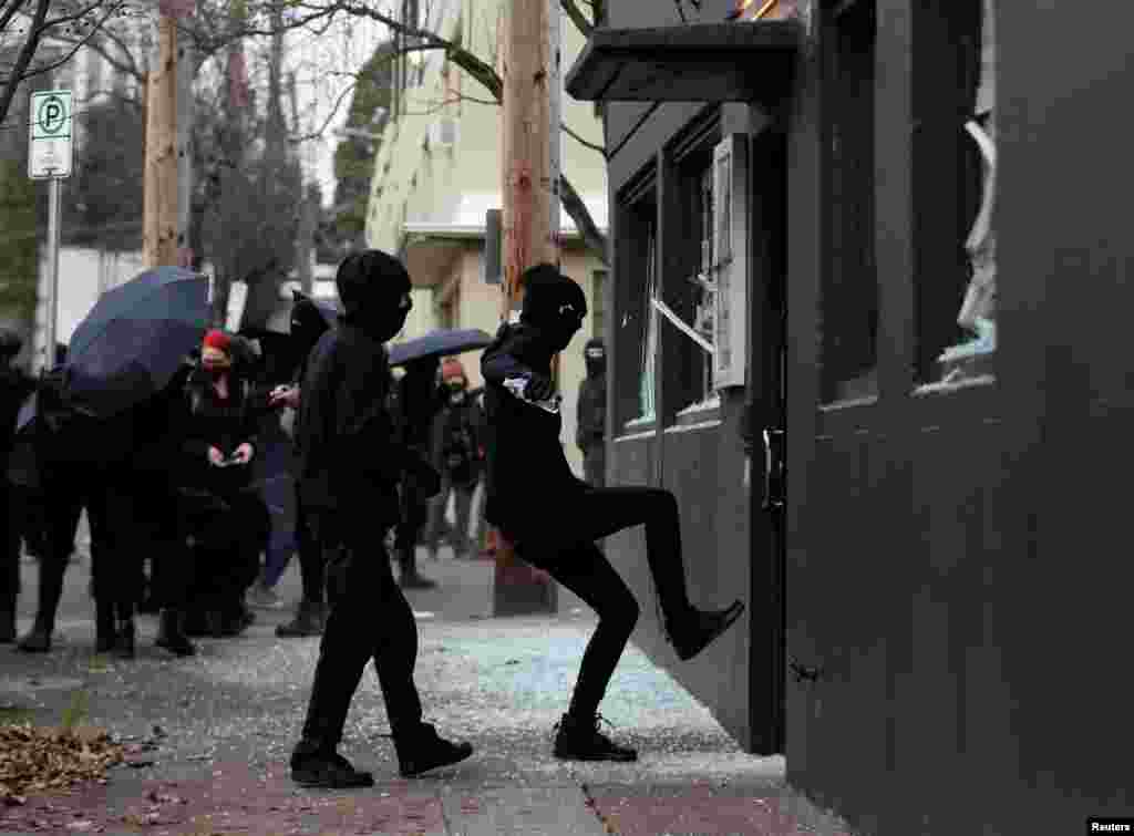 Protesters smash windows at Democratic Party of Oregon headquarters during a protest after the inauguration of U.S. President Joe Biden, in Portland, Oregon, Jan. 20, 2021.