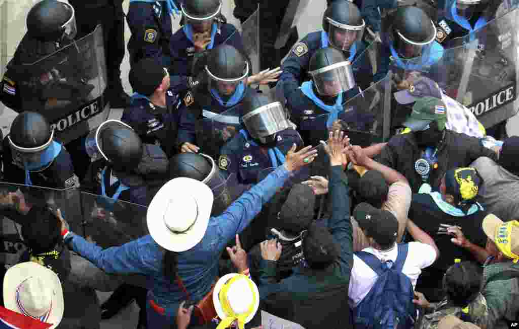Anti-government protesters scuffle with riot police officers during a rally at the Department of Special Investigation on the outskirts of Bangkok, Dec. 23, 2013.