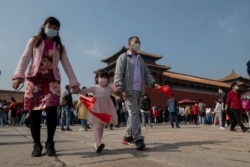 Para wisatawan mengenakan masker saat melewatkan liburan "Pekan Emas" mereka di sekitar Kota Terlarang, China, 1 Oktober 2020.