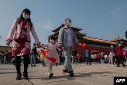 Para wisatawan mengenakan masker saat melewatkan liburan "Pekan Emas" mereka di sekitar Kota Terlarang, China, 1 Oktober 2020.