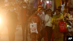 People wearing face masks as a precaution against the coronavirus shop at a market place in Jammu, India, Nov. 22, 2021.